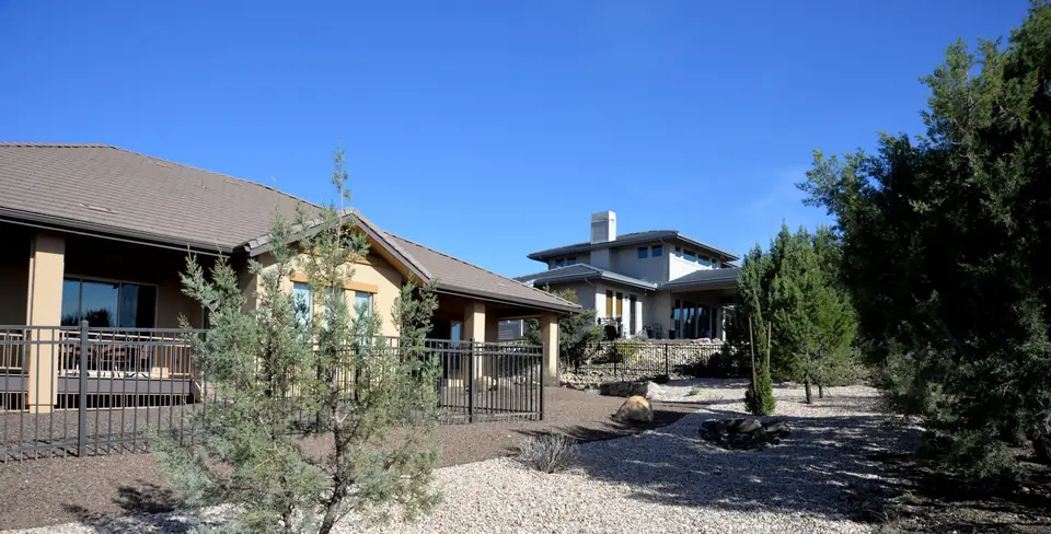Clean, weed-free gravel yard with desert trees in front of a stucco home in the Prescott area